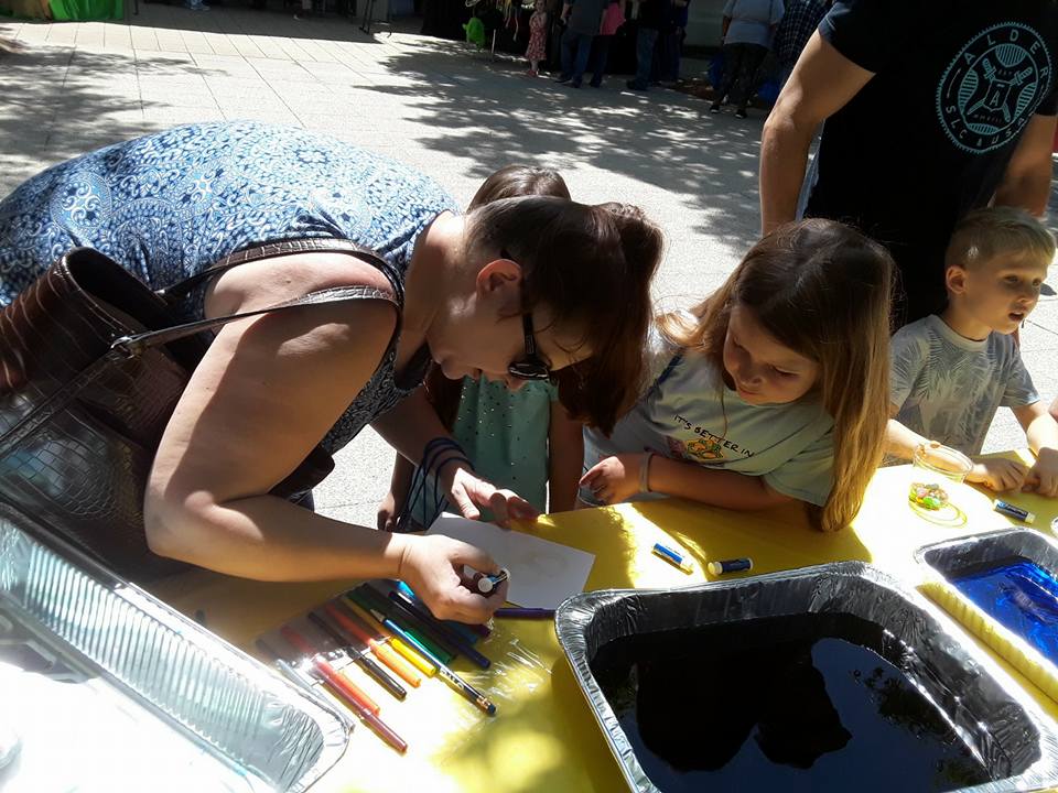 Photo shows a mother and daughter on the ground, working on an art activity for Earth Day at Birmingham Botanical Gardens in Alabama