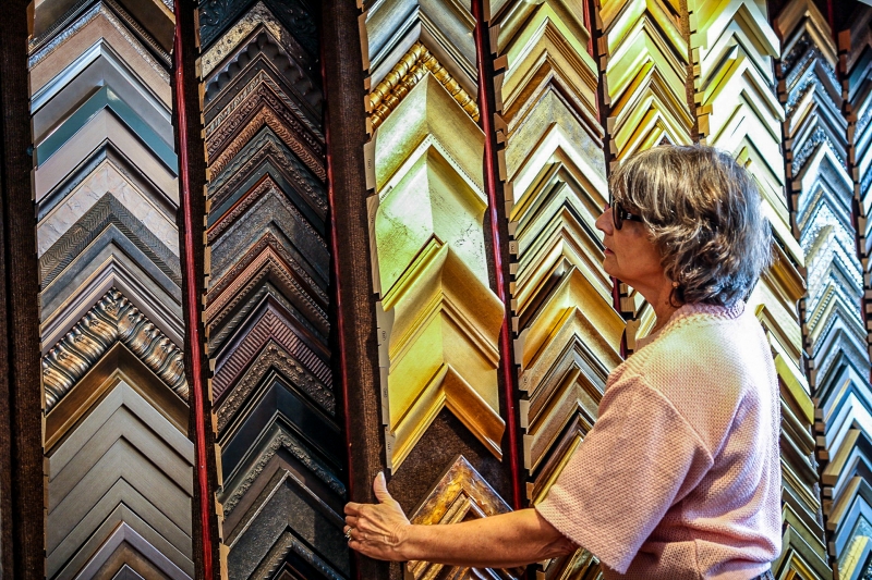 Four Corners Gallery's CEO Carla Hamilton moves panels that display framing options. 