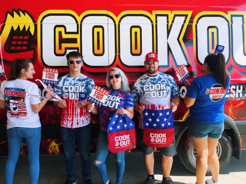 Employees pose with Cook Out merchandise 