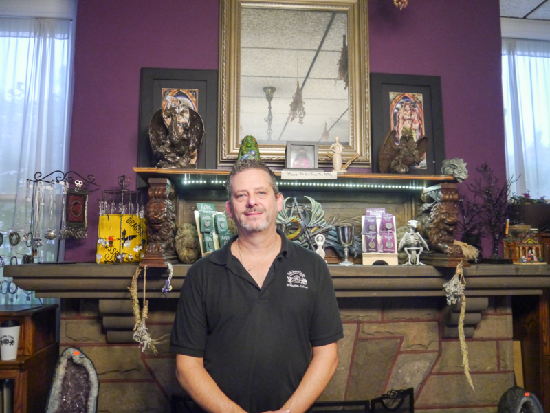 Man poses in front of fireplace and trinkets
