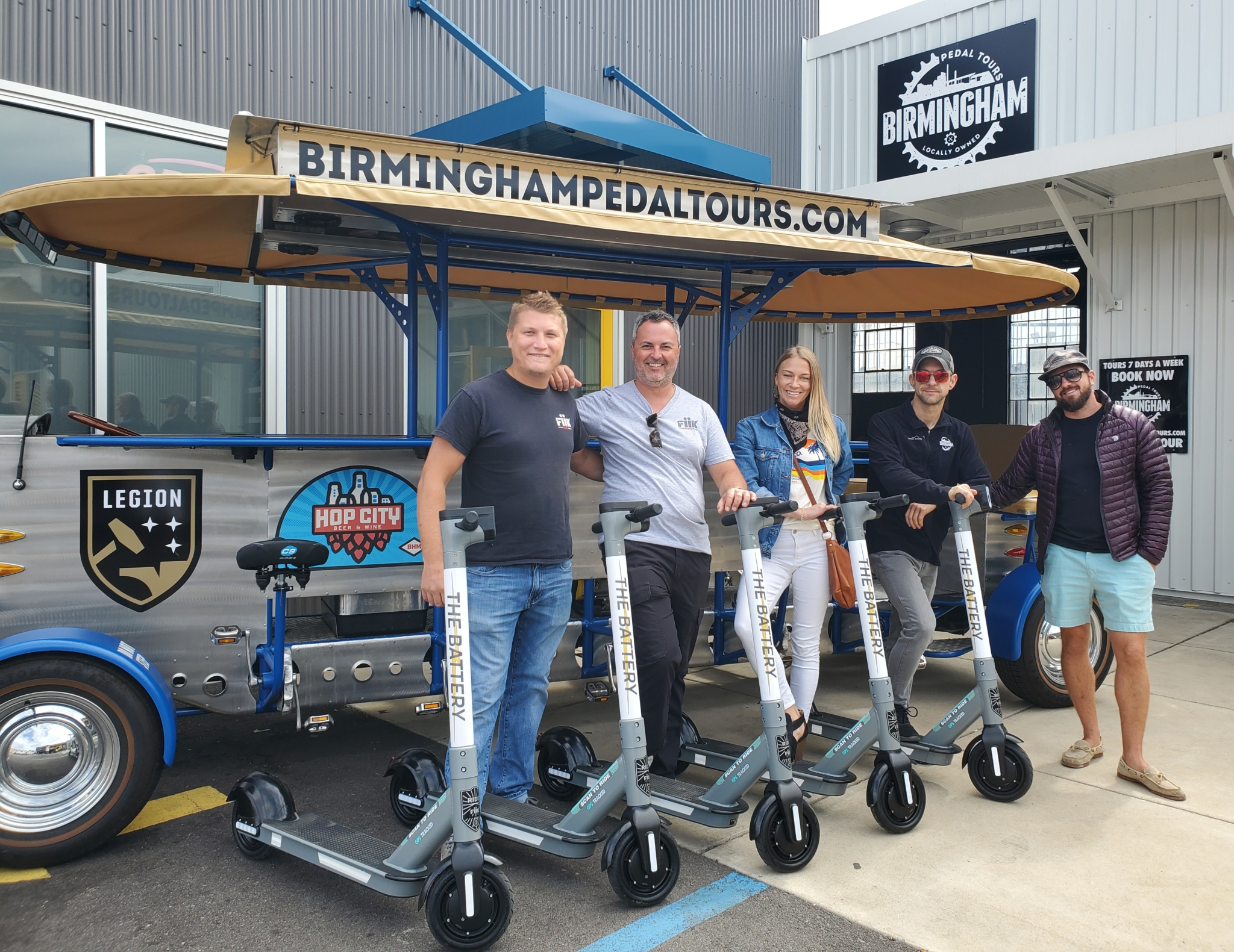 Owners of Birmingham Pedal Tours and Ride Fiik stand together around the scooters for a photo