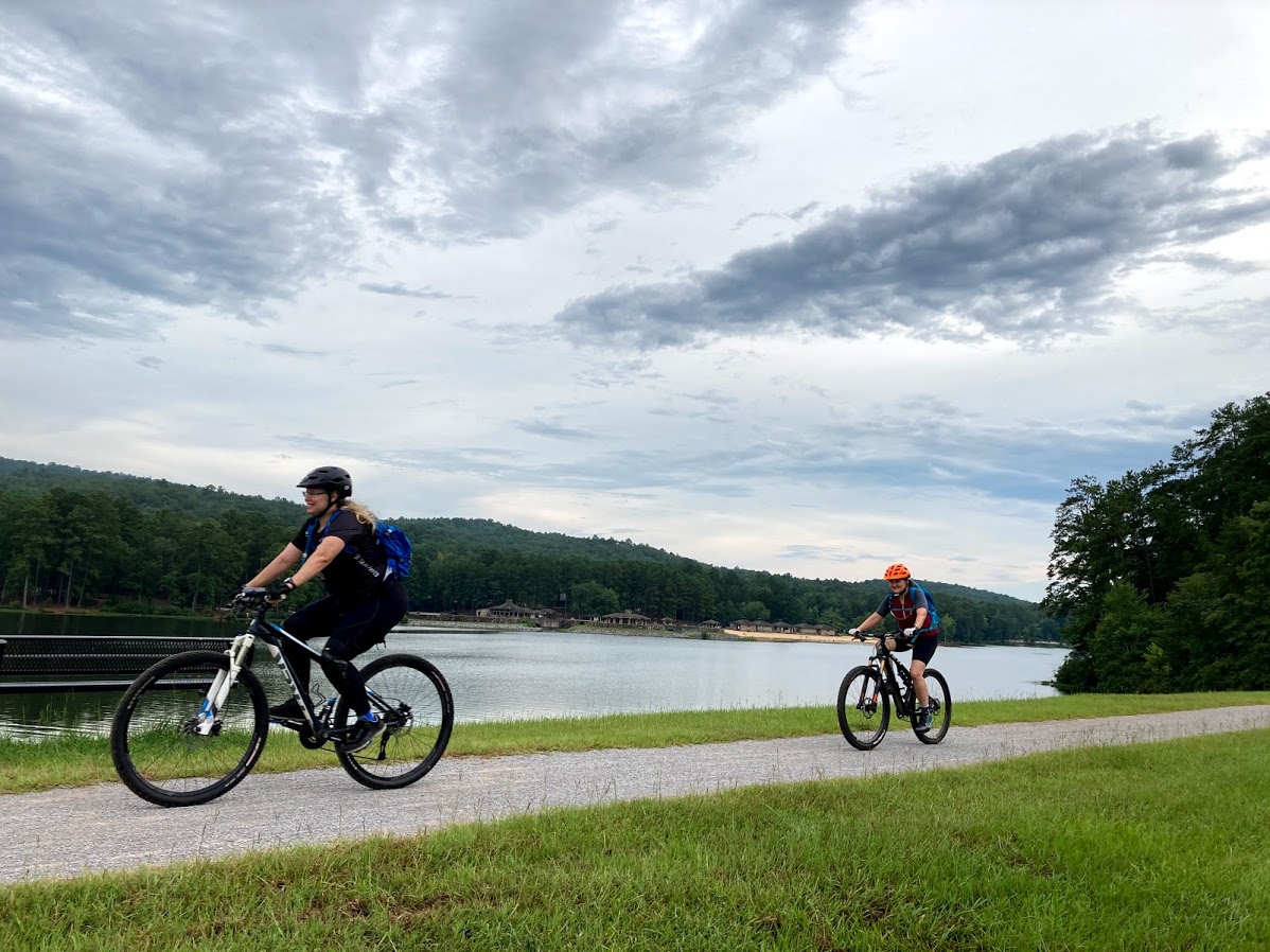 Two people biking in front of a lake