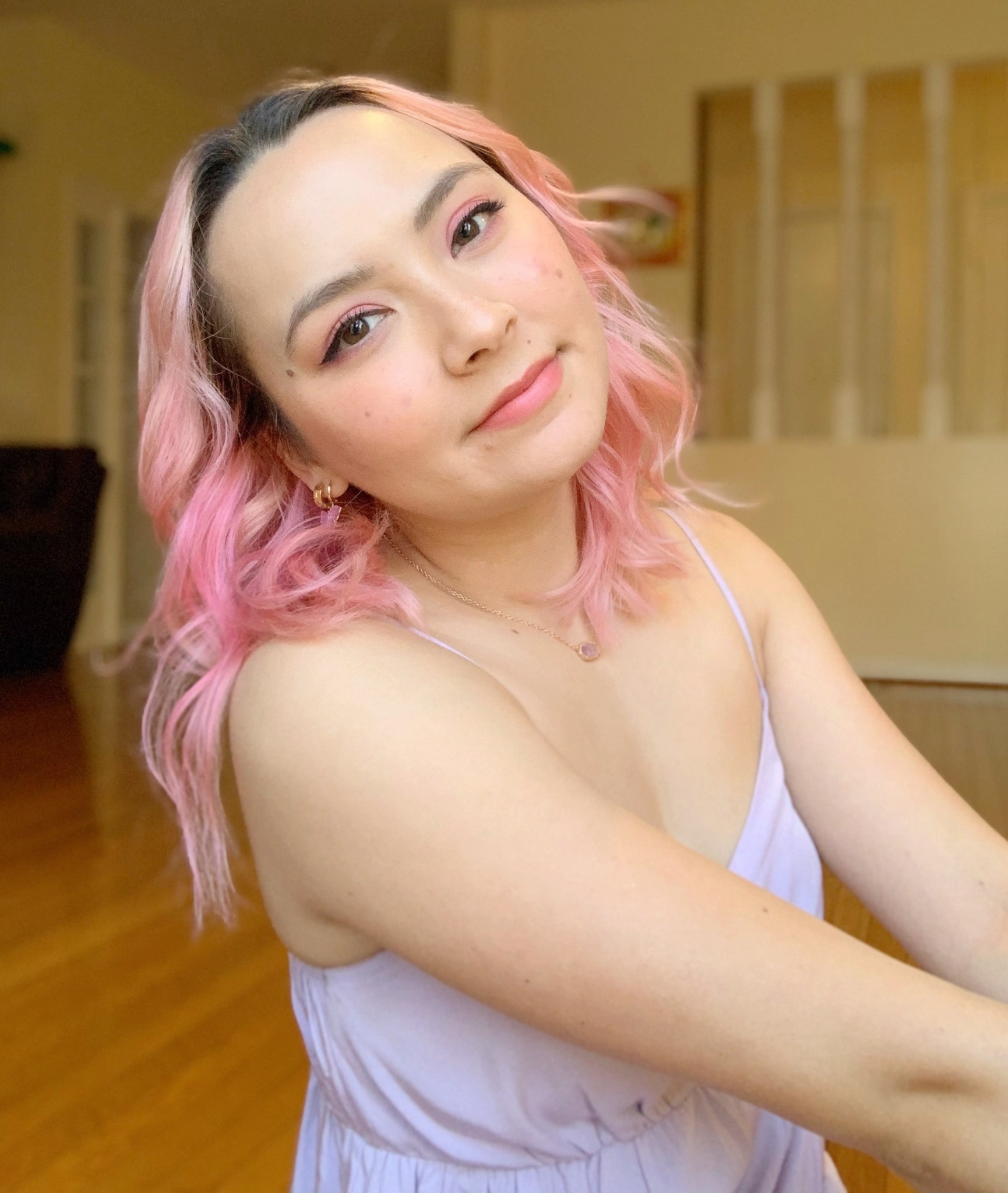 Jacqueline Le smiling slightly at the camera with pastel pink hair