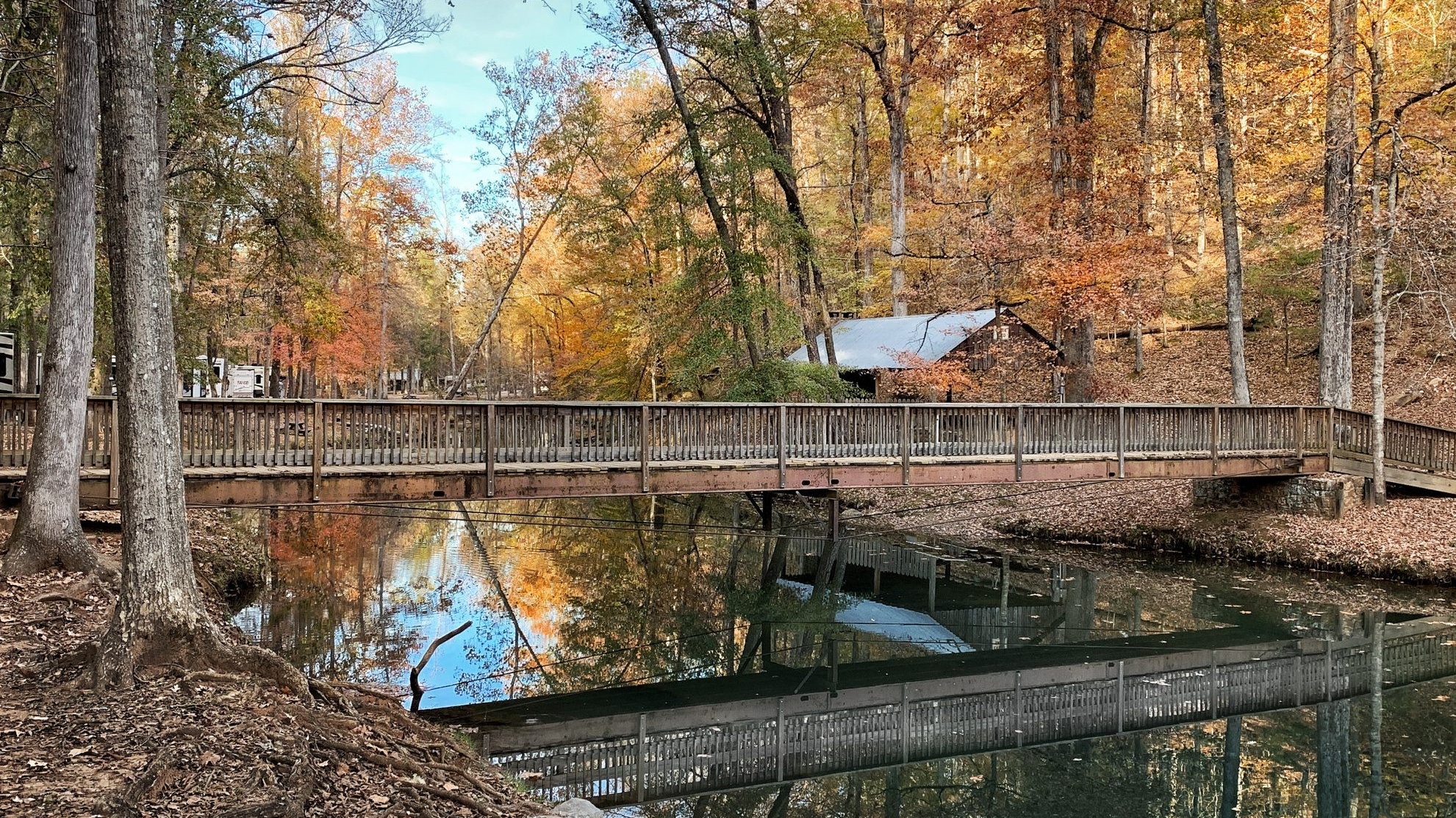 Picture of bridge over a lake with trees changing colors in the background
