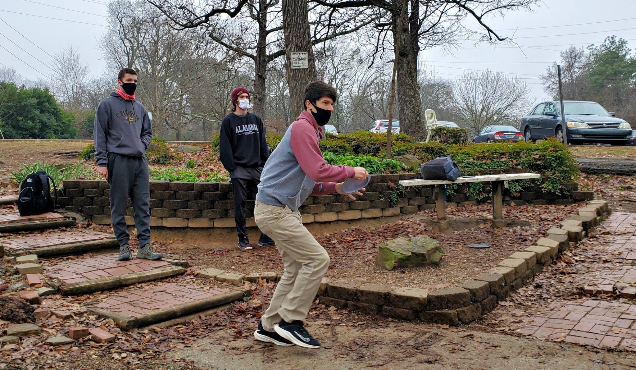 Three disc golf players throwing disc at George Ward Park.
