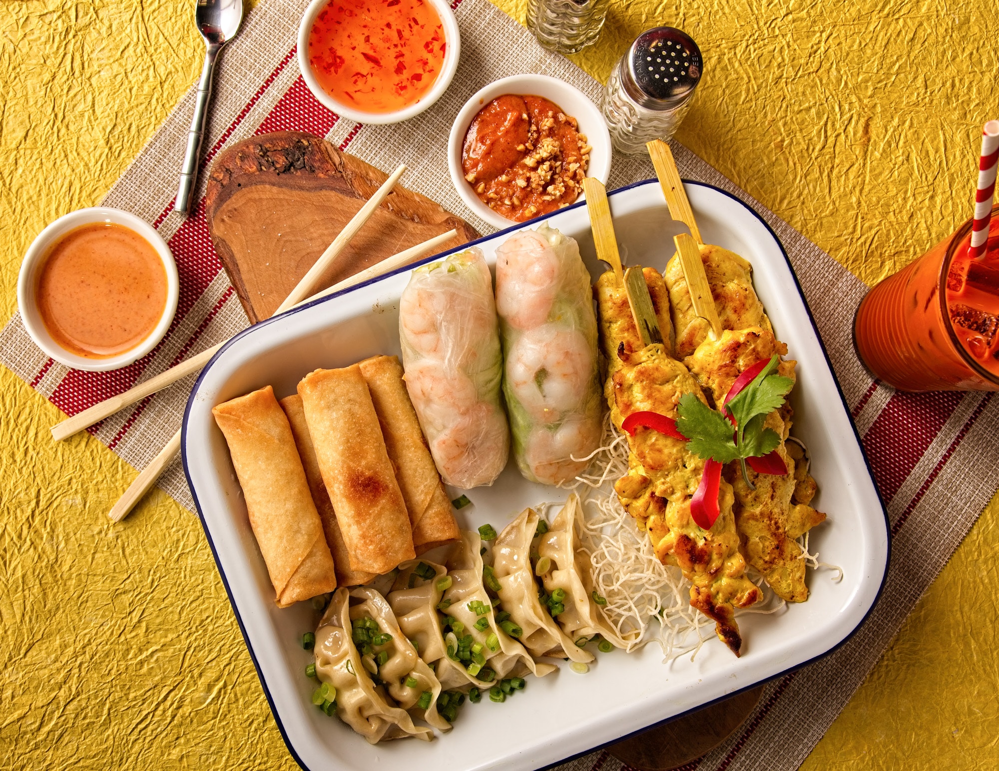 Platter with Thai appetizers of chicken satay, spring rolls, dumplings, and sauce - Birmingham Thai restaurant