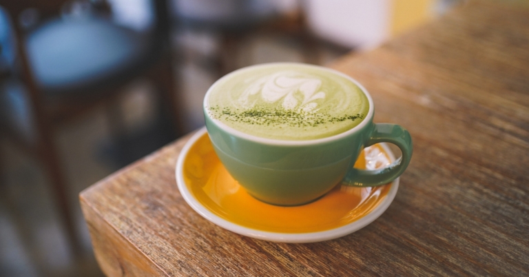 green ceramic mug with saucer on brown wooden table