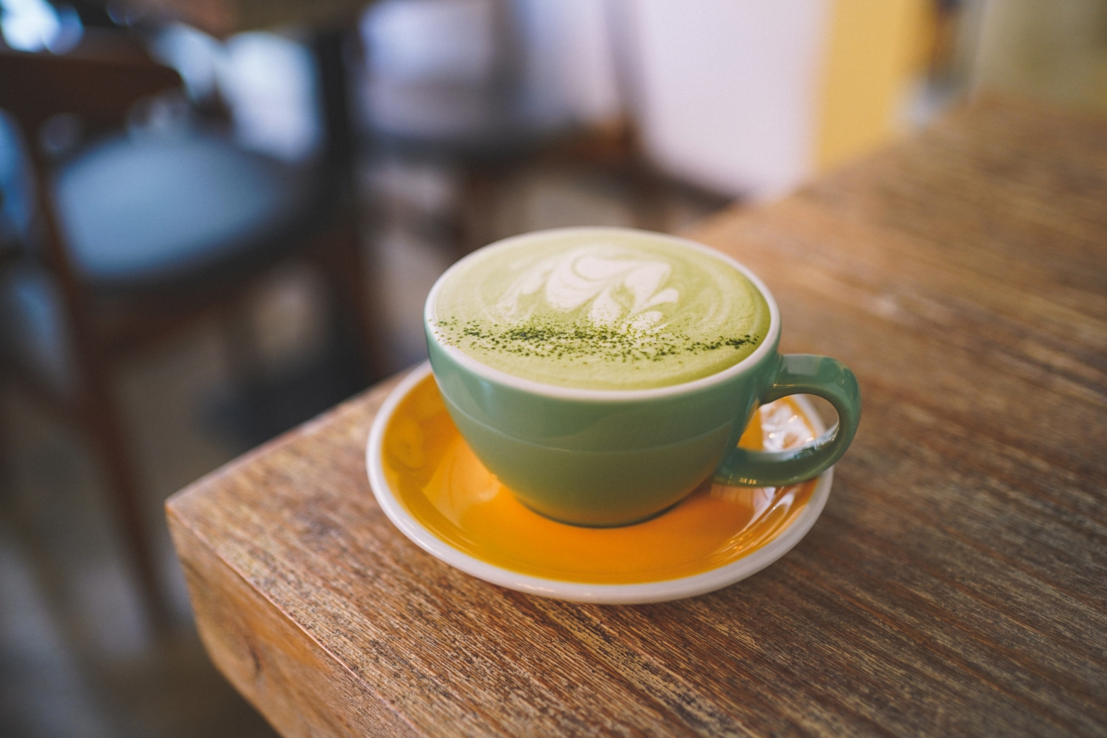 green ceramic mug with saucer on brown wooden table
