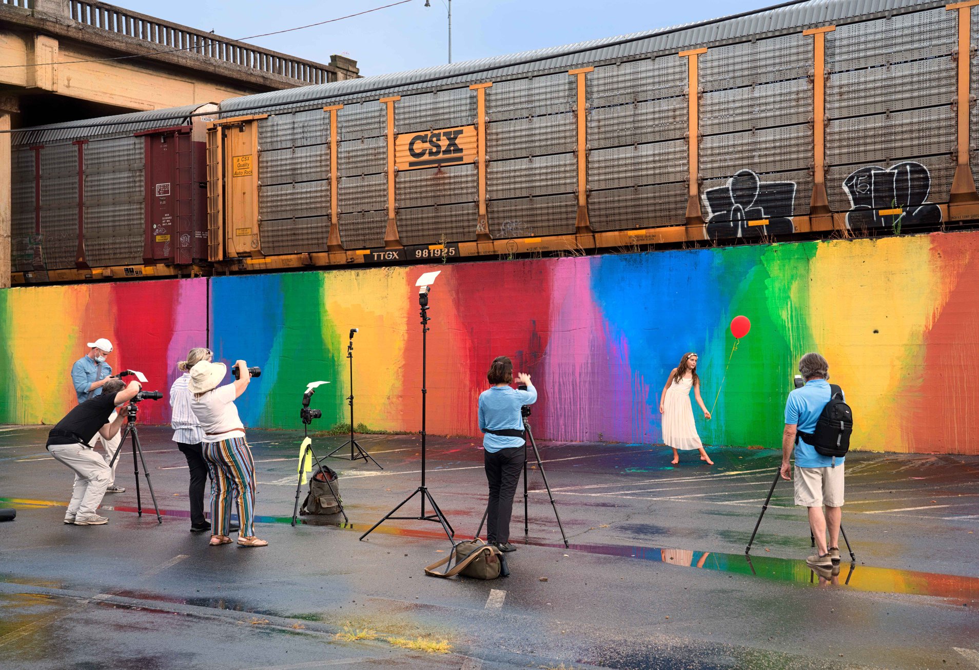 Flash photography class takes pictures of a student against a rainbow wall