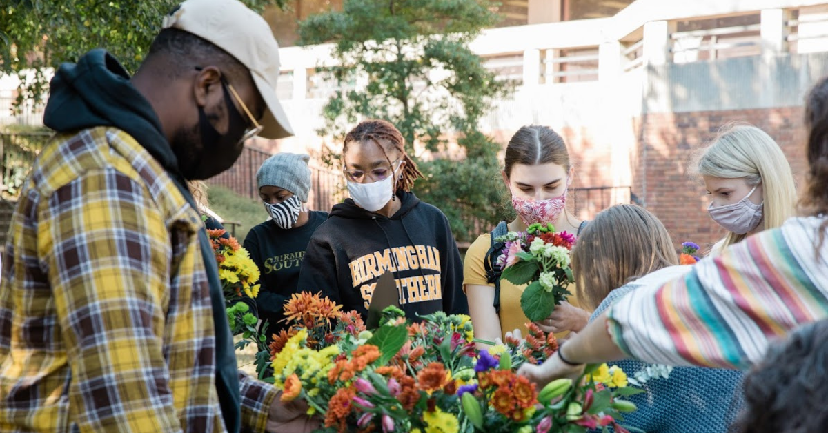 Students wearing face masks at Birmingham Southern shirts in front of flowers - BSC's articulation agreements