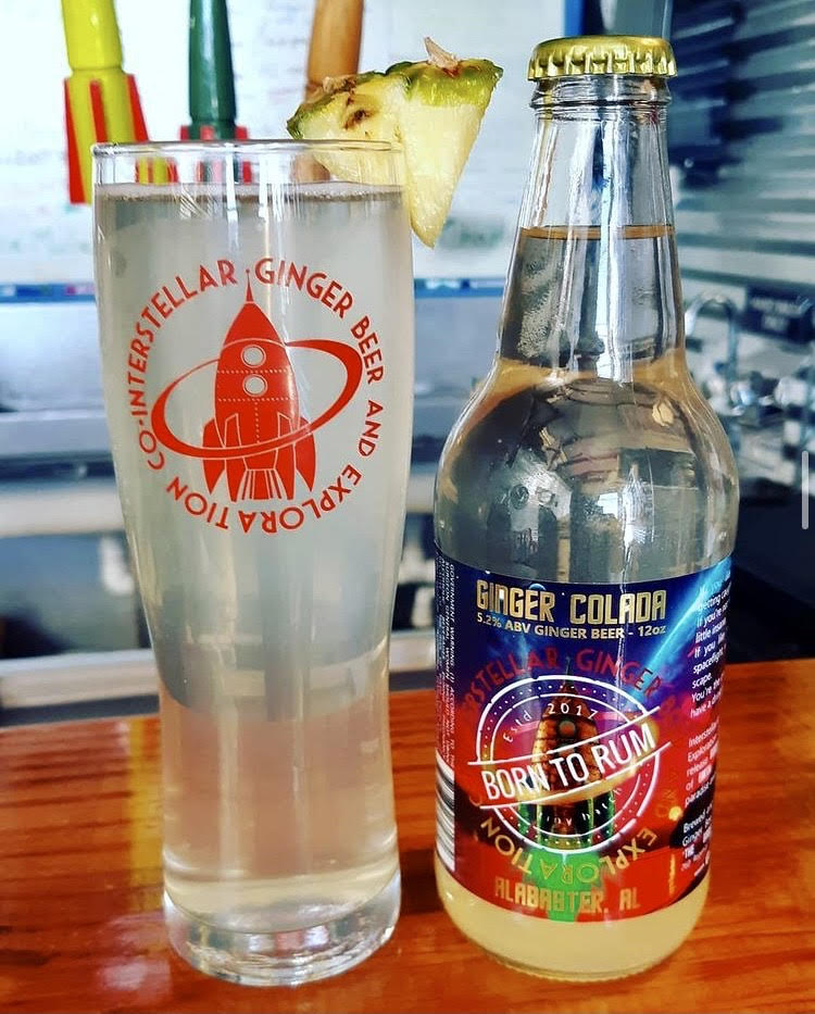 a bottle next to a pint glass of Interstellar's Ginger Colada Ginger Beer