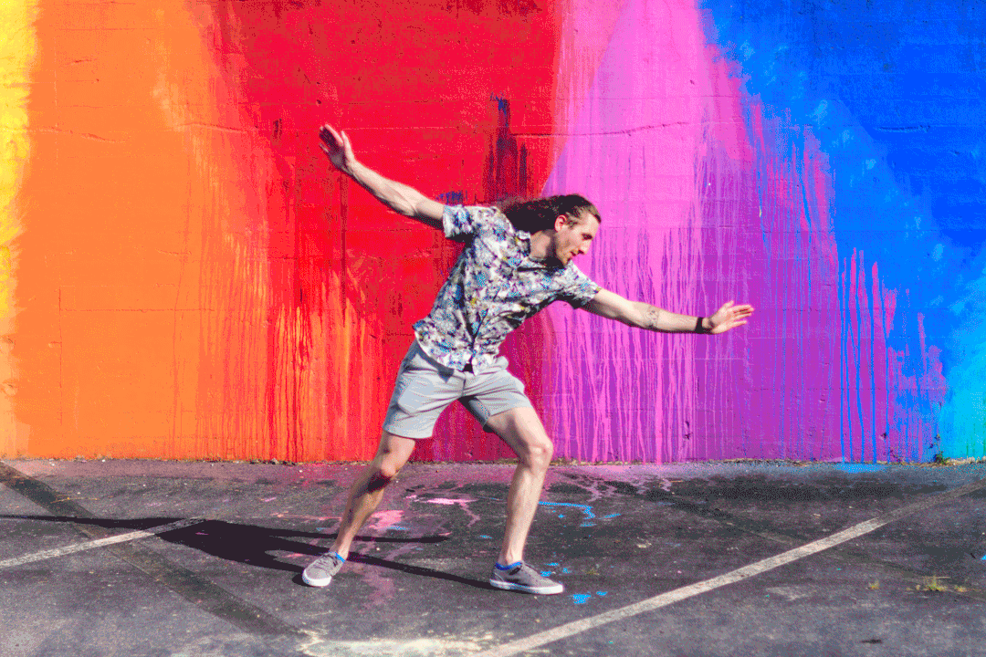 Trevor does cartwheels in front of the rainbow wall.