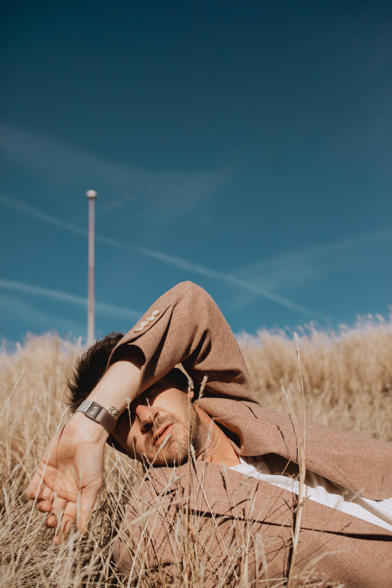 man lying on the ground under blue sky