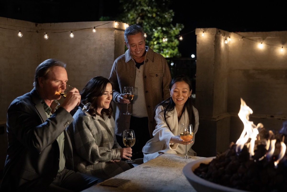 Two couple enjoy glasses of wine by a tabletop firepit at a hotel property in Ridgeland, Mississippi